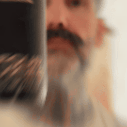 Bearded man applying Beardbrand Four Vices Cologne rollerball to his neck and showing the bottle.