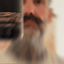 Bearded man applying Beardbrand Norse Winter Cologne rollerball to his neck and showing the bottle.