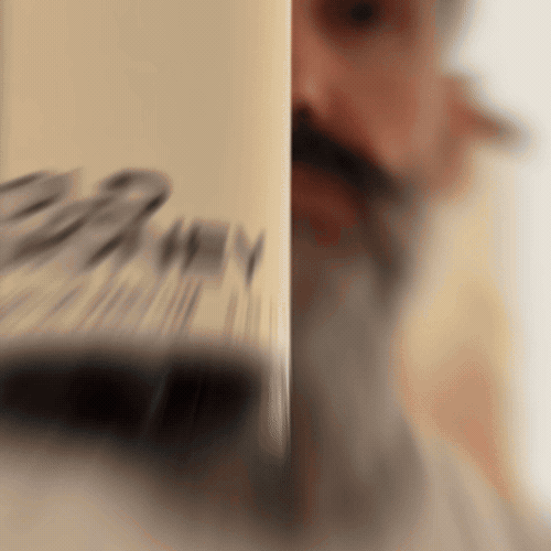 Bearded man applying Beardbrand Old Money Cologne rollerball to his neck and showing the bottle.